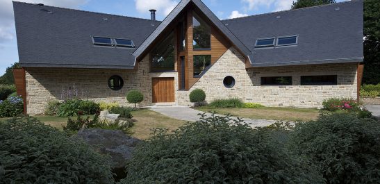 Maison d'architecte équipée de menuiseries en bois aluminium Minco. Fenêtre ronde oeil de boeuf sur la facade.